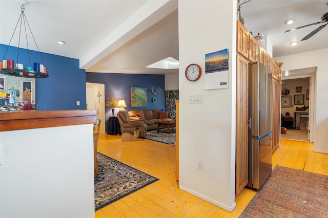 kitchen featuring light hardwood / wood-style floors, stainless steel refrigerator, and ceiling fan with notable chandelier