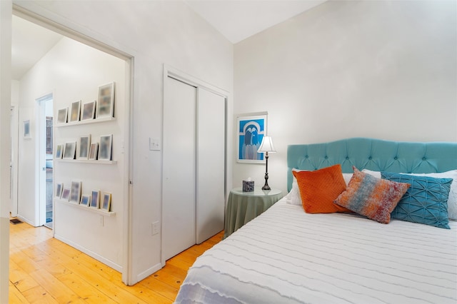 bedroom featuring a closet, light hardwood / wood-style floors, and vaulted ceiling