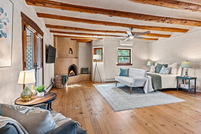 living room featuring a large fireplace, an AC wall unit, a baseboard radiator, and light wood-type flooring