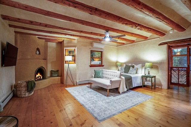 bedroom featuring an AC wall unit, ceiling fan, light wood-type flooring, and baseboard heating