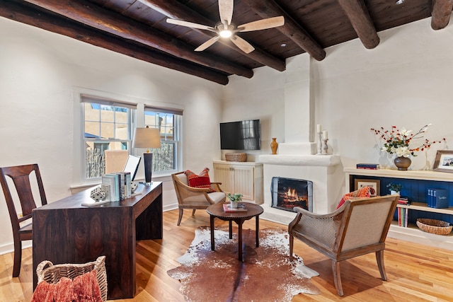 interior space featuring wood ceiling, a large fireplace, ceiling fan, beamed ceiling, and light hardwood / wood-style floors