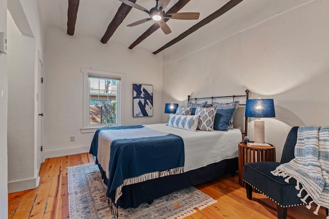 bedroom featuring hardwood / wood-style floors, lofted ceiling with beams, and ceiling fan