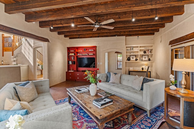 living room with ceiling fan, built in features, and beamed ceiling