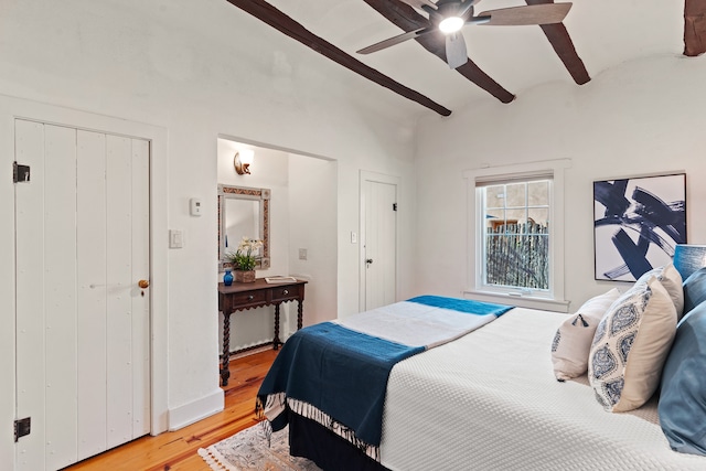 bedroom with light hardwood / wood-style floors, vaulted ceiling with beams, and ceiling fan