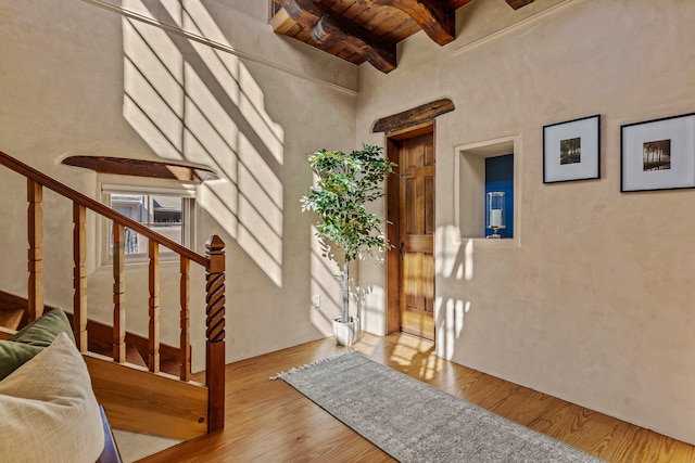 entryway featuring a towering ceiling, beamed ceiling, light wood-type flooring, and wooden ceiling