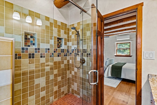 bathroom featuring an AC wall unit, a shower with shower door, and hardwood / wood-style floors