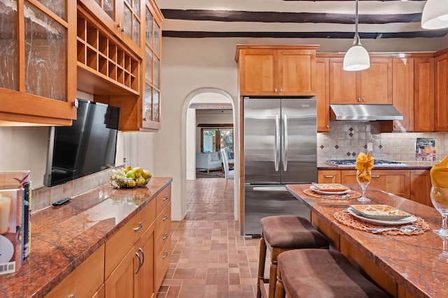 kitchen featuring tasteful backsplash, appliances with stainless steel finishes, dark stone counters, and pendant lighting