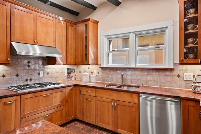 kitchen with decorative backsplash, appliances with stainless steel finishes, dark stone countertops, beamed ceiling, and sink