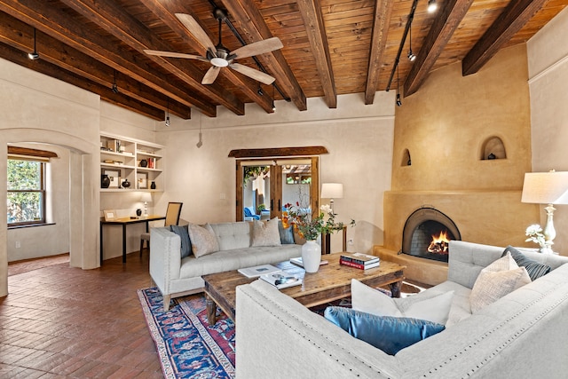 living room with wood ceiling, beamed ceiling, a large fireplace, and built in shelves