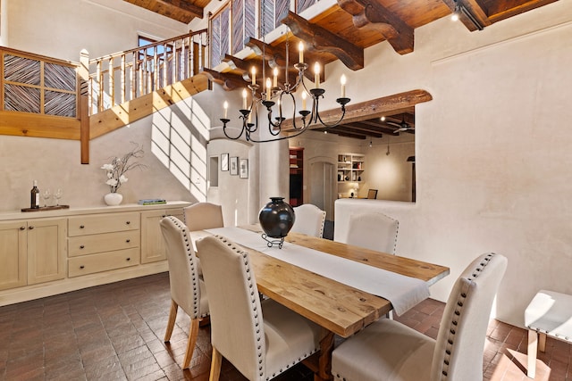 dining space featuring beamed ceiling, a high ceiling, a notable chandelier, and wood ceiling