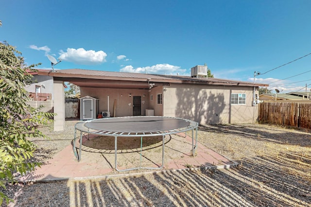 rear view of property with a storage shed, a fenced backyard, metal roof, an outbuilding, and a trampoline