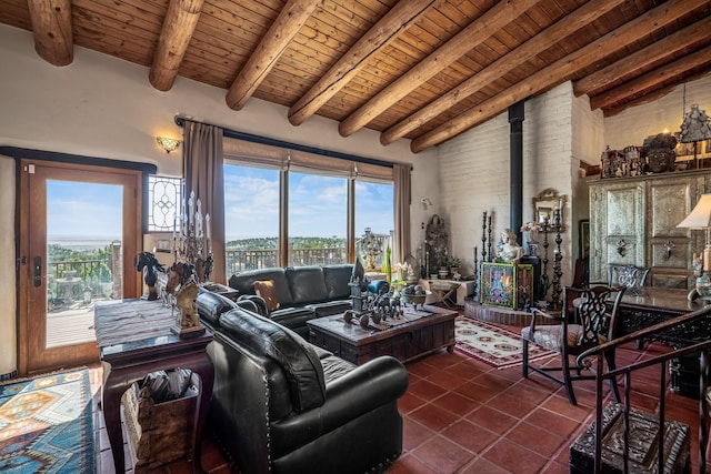 living room with wood ceiling, lofted ceiling with beams, a wood stove, dark tile patterned floors, and a healthy amount of sunlight