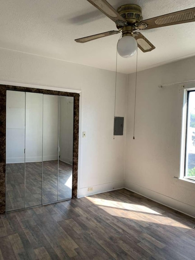 unfurnished bedroom featuring electric panel, ceiling fan, dark hardwood / wood-style floors, a textured ceiling, and a closet