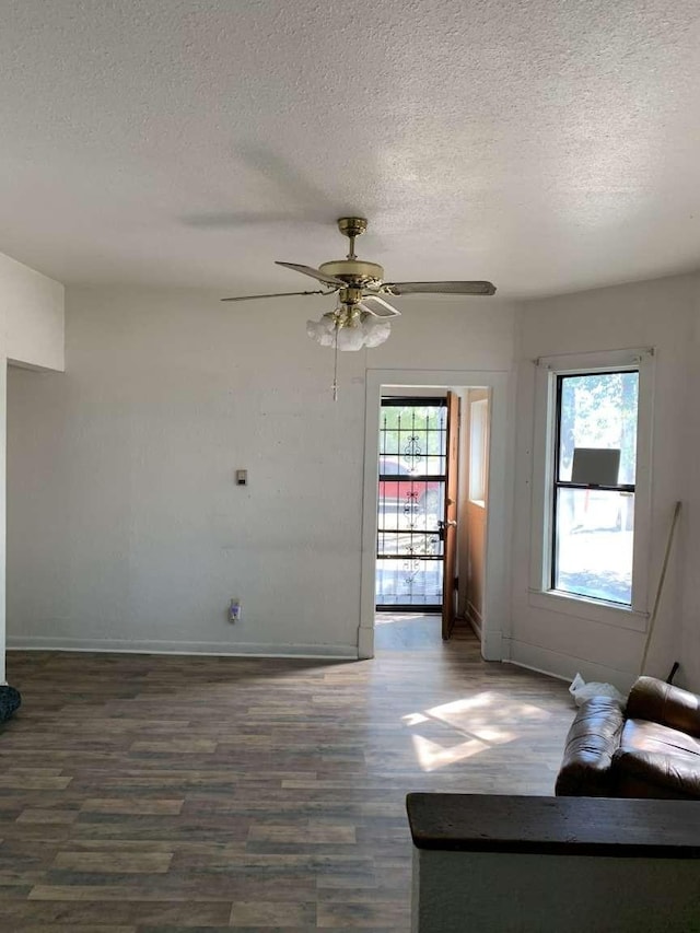 unfurnished living room with ceiling fan, dark hardwood / wood-style flooring, and a textured ceiling