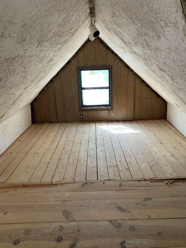 bonus room featuring wood walls, light hardwood / wood-style flooring, and vaulted ceiling