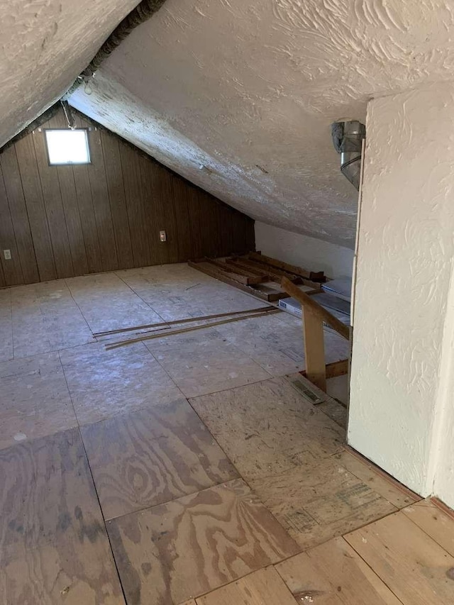 additional living space featuring lofted ceiling and wooden walls