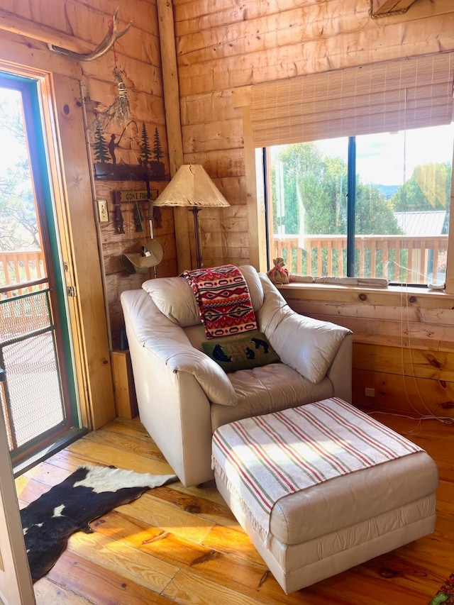 sitting room with hardwood / wood-style flooring and wooden walls