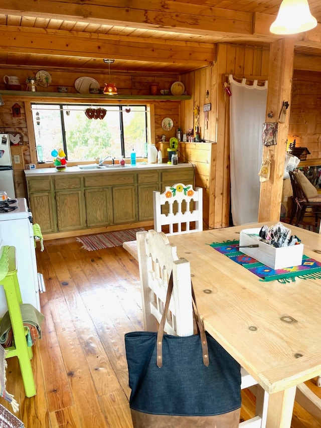 dining room featuring sink, wooden ceiling, light wood-type flooring, and wooden walls