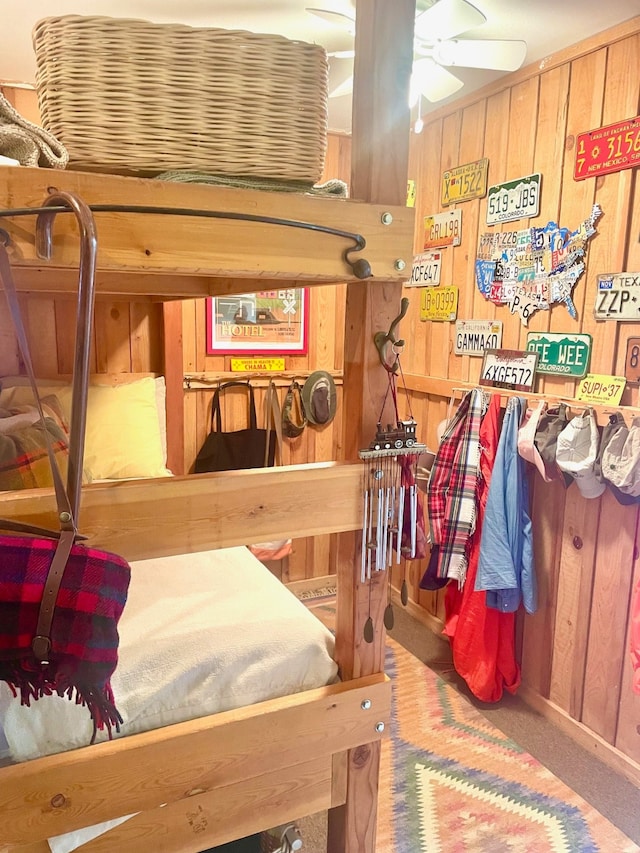 bedroom featuring ceiling fan, carpet floors, and wood walls