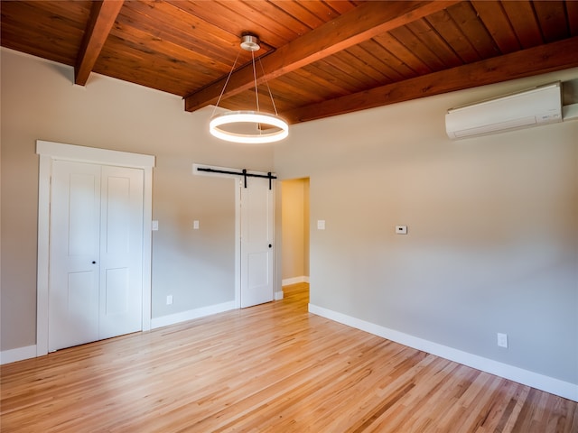 interior space featuring an AC wall unit, beamed ceiling, wooden ceiling, a barn door, and light wood-type flooring