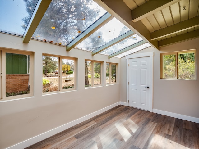 unfurnished sunroom featuring lofted ceiling with beams and a wealth of natural light