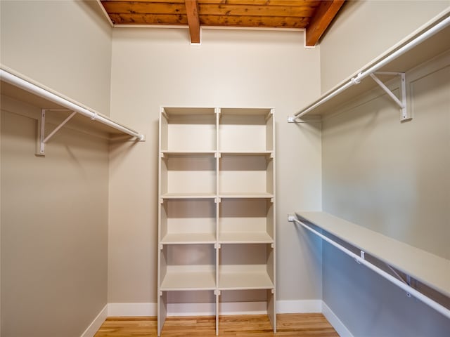 spacious closet with beamed ceiling and light hardwood / wood-style flooring