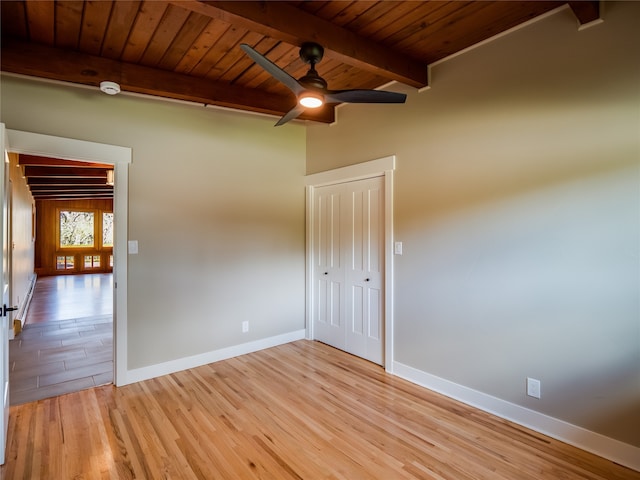 empty room featuring beam ceiling, wood ceiling, light wood-type flooring, and ceiling fan