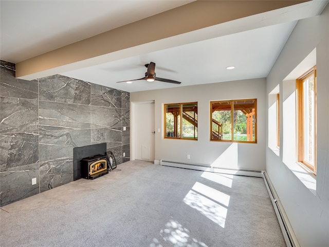 unfurnished living room featuring a wood stove, carpet floors, baseboard heating, and ceiling fan