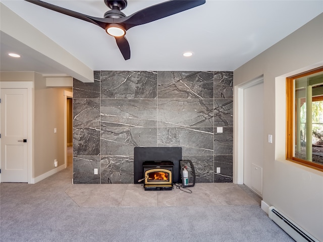 unfurnished living room featuring tile walls, a baseboard heating unit, a wood stove, and ceiling fan