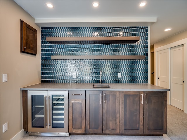 bar featuring dark brown cabinets, sink, beverage cooler, and backsplash