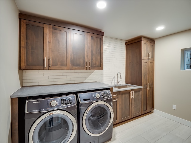 clothes washing area featuring independent washer and dryer, cabinets, and sink