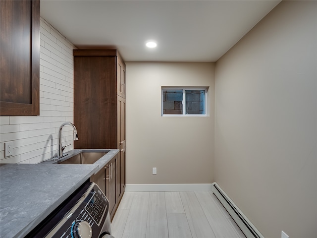 clothes washing area featuring baseboard heating, washer / clothes dryer, sink, and light wood-type flooring