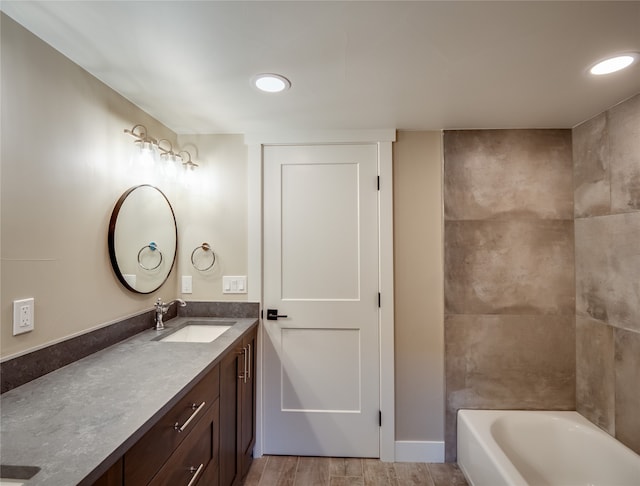 bathroom featuring vanity, wood-type flooring, and a bath