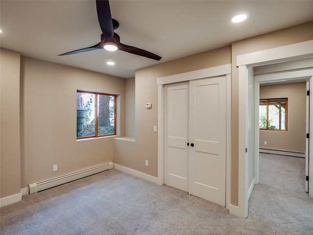 unfurnished bedroom featuring multiple windows, a baseboard radiator, and ceiling fan