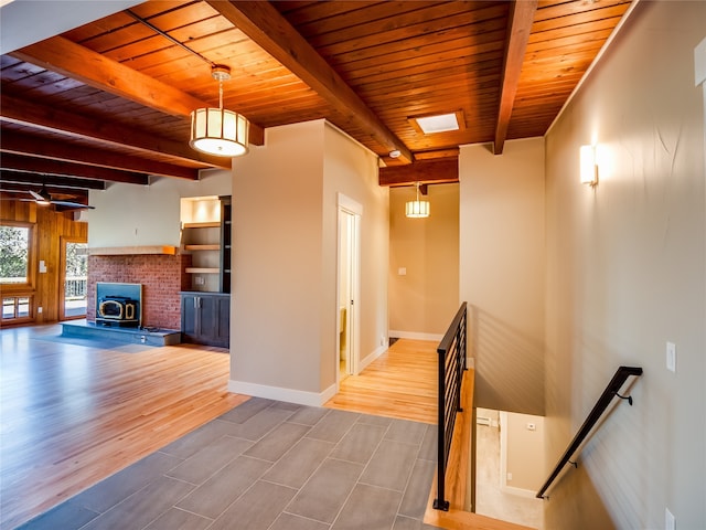 stairs featuring a skylight, wood ceiling, a wood stove, hardwood / wood-style floors, and beam ceiling