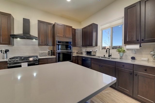 kitchen with wall chimney range hood, stainless steel appliances, sink, and backsplash