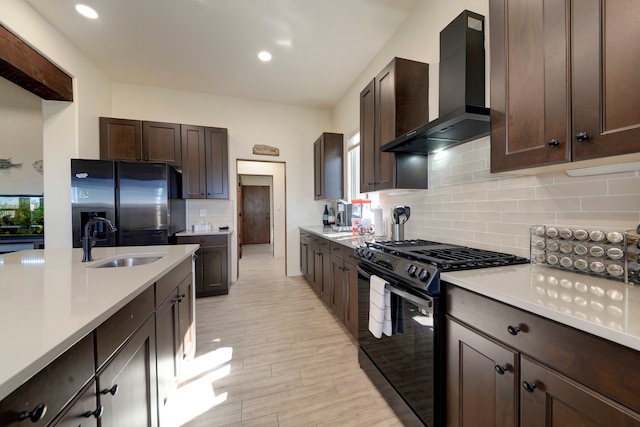 kitchen featuring tasteful backsplash, light wood-type flooring, black appliances, wall chimney exhaust hood, and sink