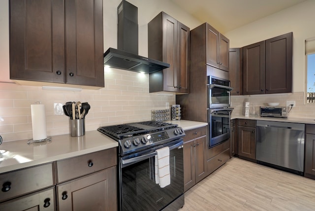 kitchen with stainless steel appliances, wall chimney exhaust hood, dark brown cabinetry, decorative backsplash, and light hardwood / wood-style flooring