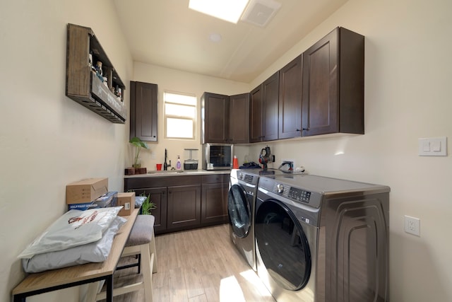 laundry room featuring cabinets, sink, washer and clothes dryer, and light wood-type flooring