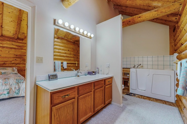 bathroom featuring vanity, a bathtub, separate washer and dryer, and log walls