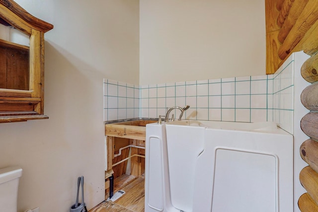 bathroom featuring toilet, wood-type flooring, and backsplash