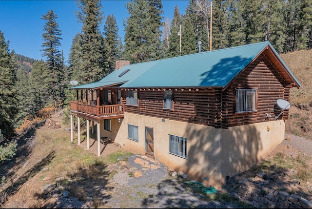 12 Pine Ln, Terrero, NM 87573 - back of property with log siding, metal roof, a chimney, stucco siding, and a wooden deck