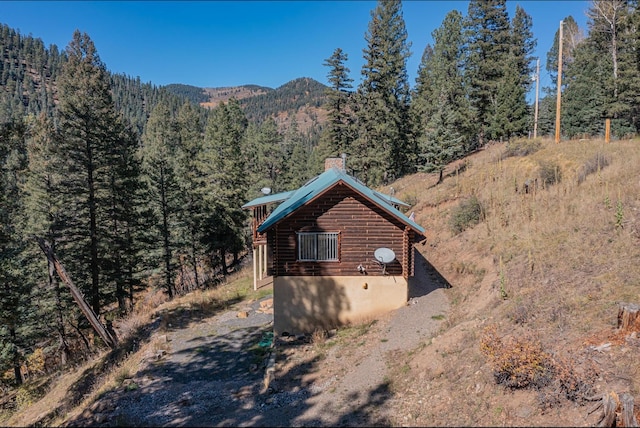 12 Pine Ln, Terrero, NM 87573 - view of side of property featuring a wooded view, a chimney, a mountain view, and log siding