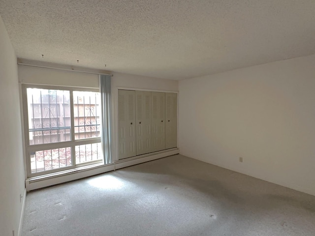 unfurnished bedroom with a textured ceiling, baseboard heating, and a closet