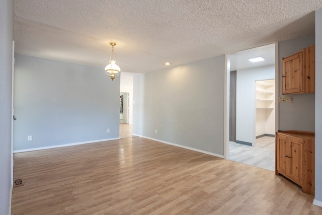 spare room featuring light hardwood / wood-style flooring and a textured ceiling