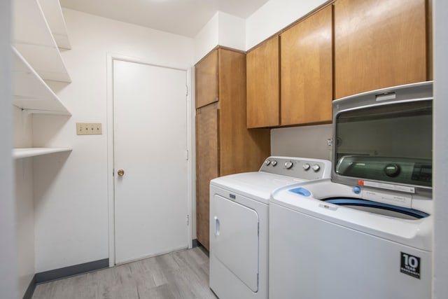 laundry area featuring cabinets, light hardwood / wood-style flooring, and separate washer and dryer