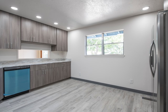 kitchen featuring appliances with stainless steel finishes, light hardwood / wood-style flooring, and a textured ceiling