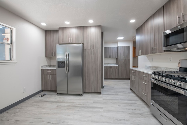 kitchen featuring light hardwood / wood-style floors, appliances with stainless steel finishes, and a textured ceiling