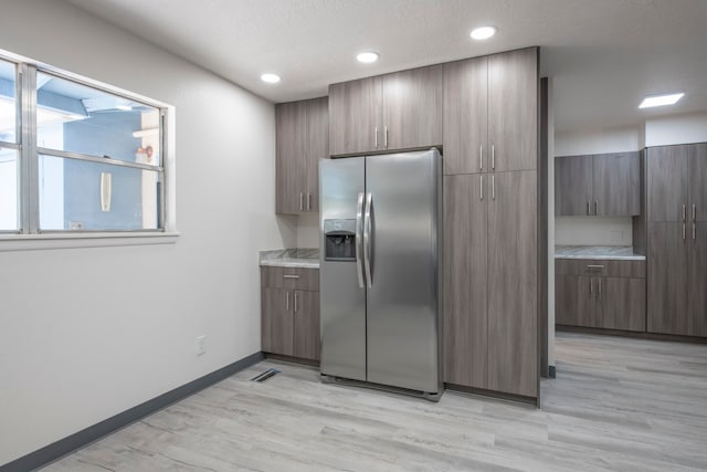 kitchen featuring stainless steel refrigerator with ice dispenser, a textured ceiling, and light hardwood / wood-style floors