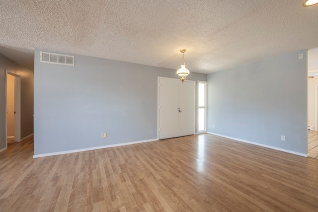 unfurnished room featuring a textured ceiling and light wood-type flooring